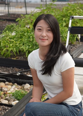 Amy kneeling next to a garden with growing plants and rocks.