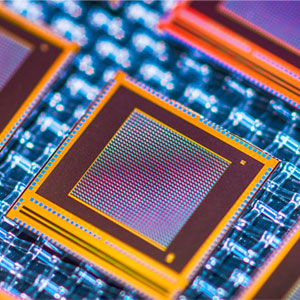 Close-up of multiple semiconductor chips with orange outlines on a blue circuit board, displaying intricate patterns.