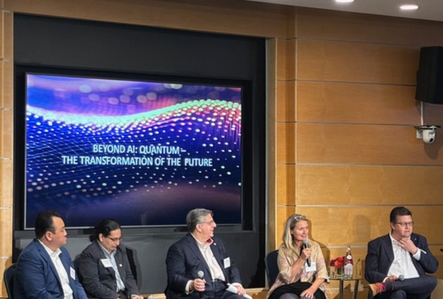 Panelists sit in front of a projector that says Beyond AI: Quantum
