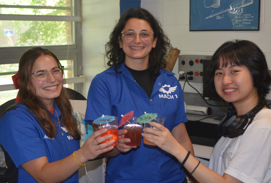 Three young women raise colorful mocktails with paper umbrellas