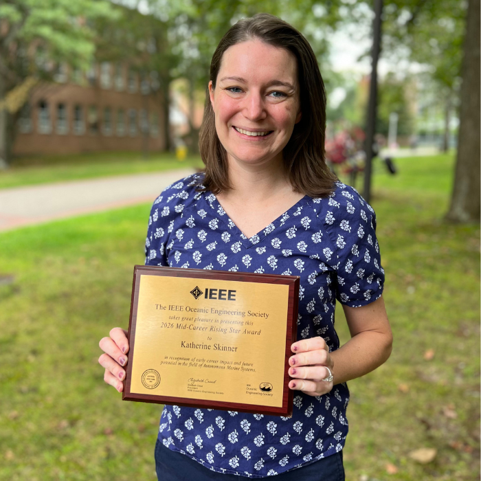 Smiling woman standing outside holding a plaque