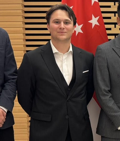 Picture of student in front a red flag in a suit