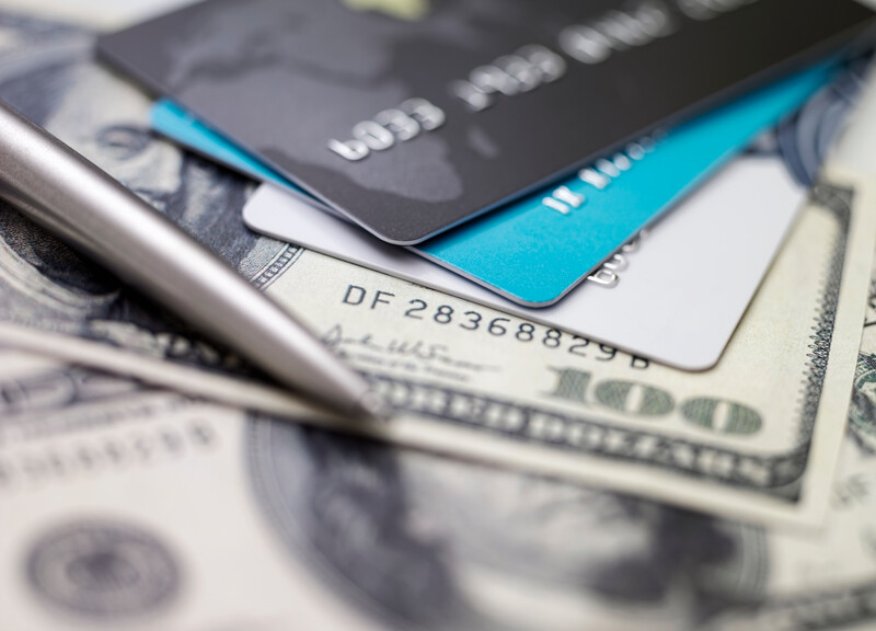 Bank cards and currency beside a pen