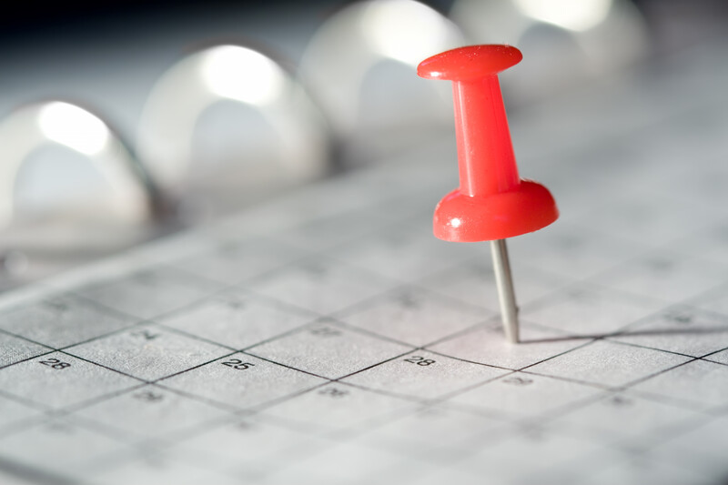A red pushpin marking a calendar date