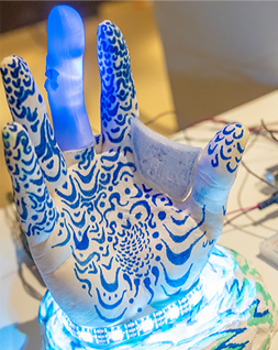 a futuristic looking blue and gray glove with four fingers, lit with blue LEDs at the base
