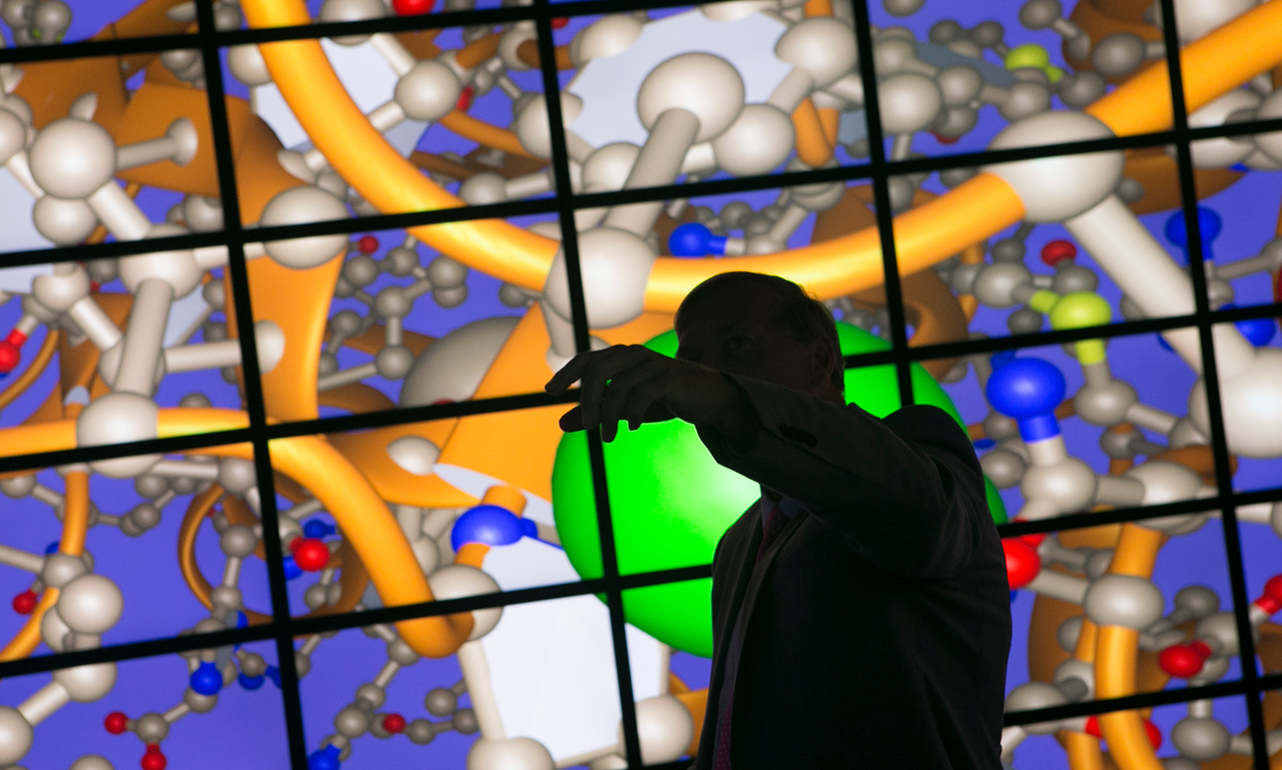 shadow of a man pointing at large computer screen.