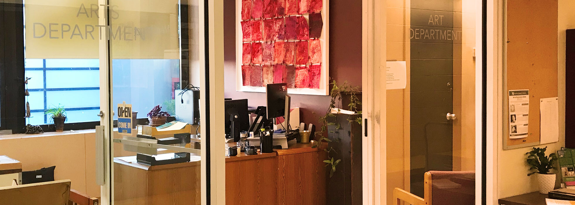 Natural light streams into the glass-walled office of the Art Department.