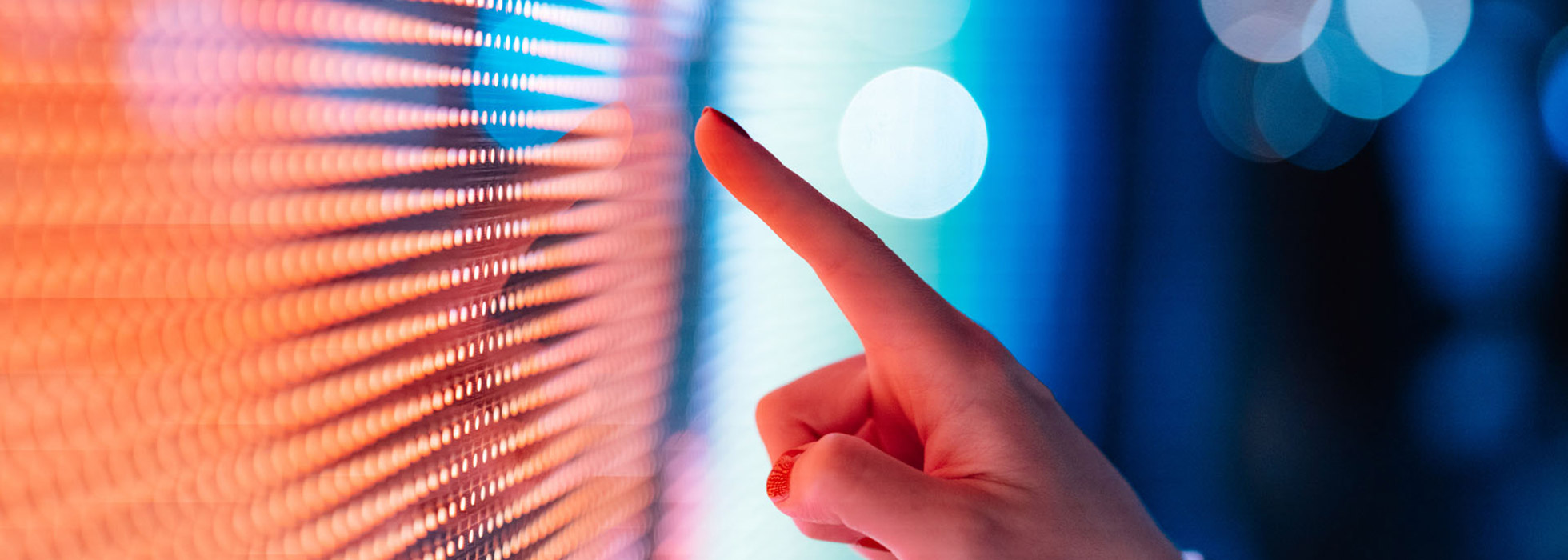 Appearing to be gently reaching out to touch the colorful monitor screen with an index finger.