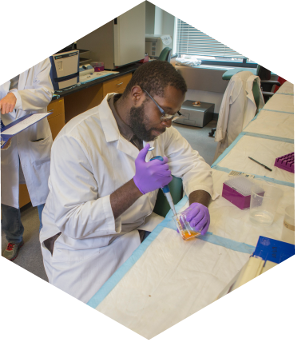 student_bench student in labcoat using a pipette