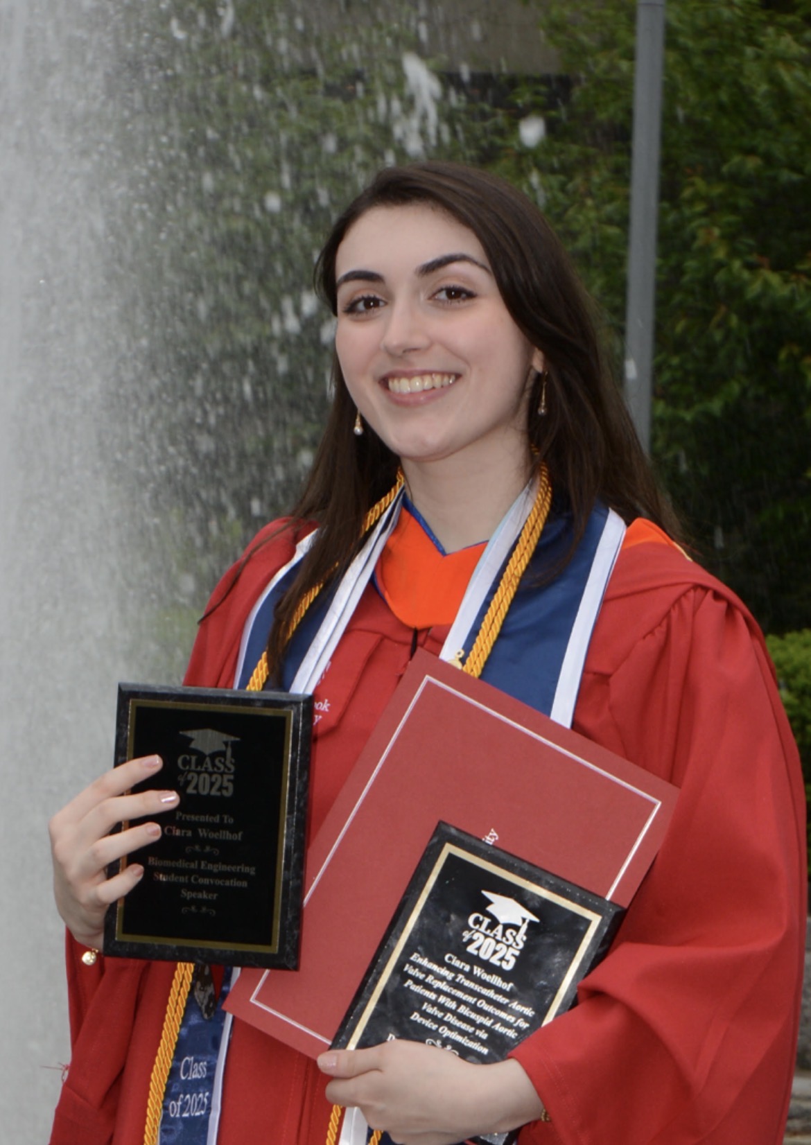 Ciara Woellhof Ciara posing with her award in graduation attire