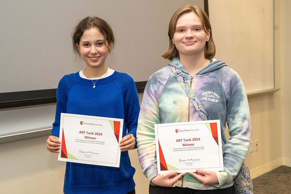 Two art tank winners standing with their certificates