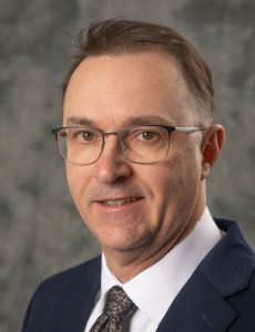 Paul Kelton Man in suit and glasses smiling