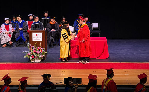 Graduation ceremony with a graduate shaking hands with a faculty member on stage.