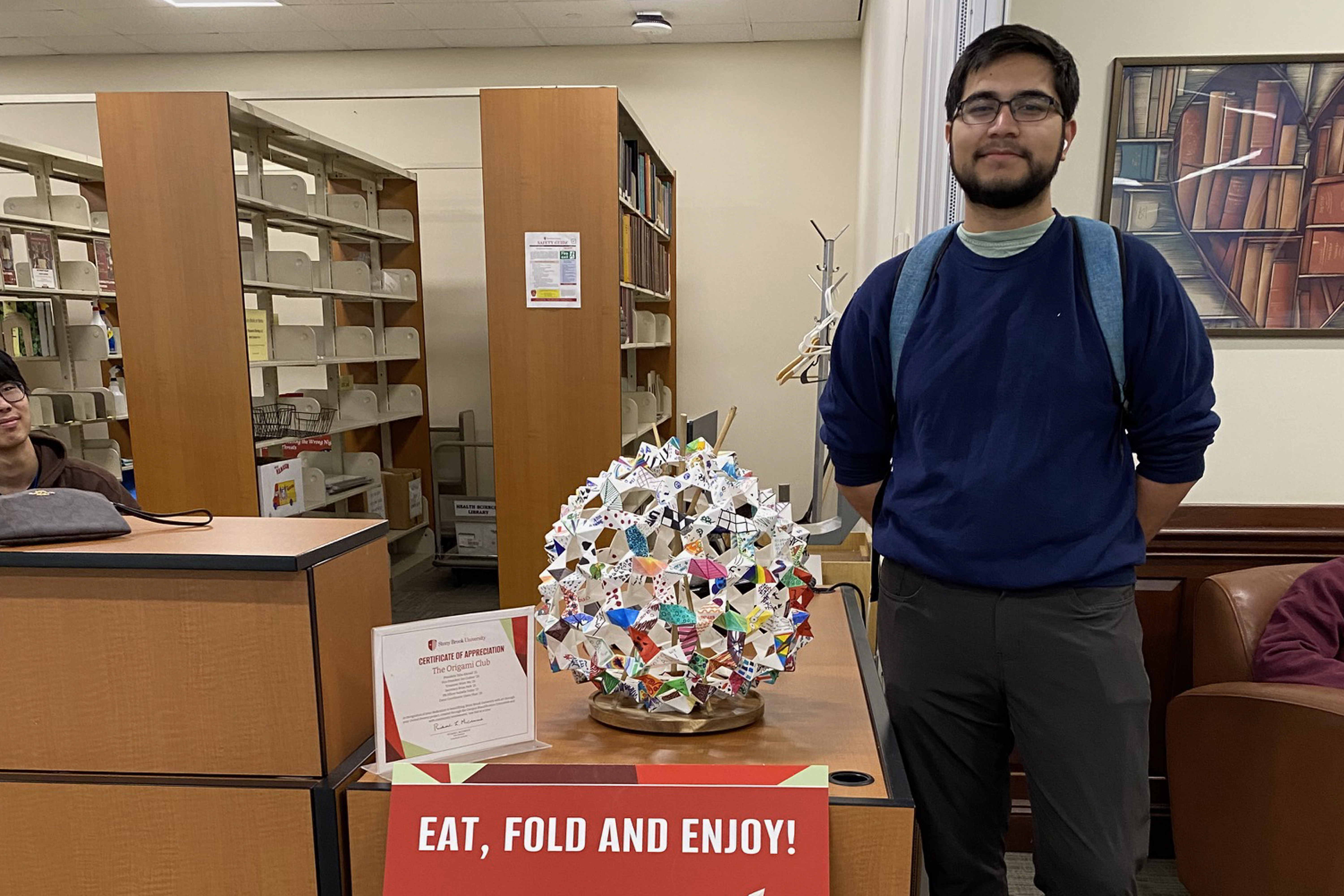 man standing in front of an art piece made with origami
