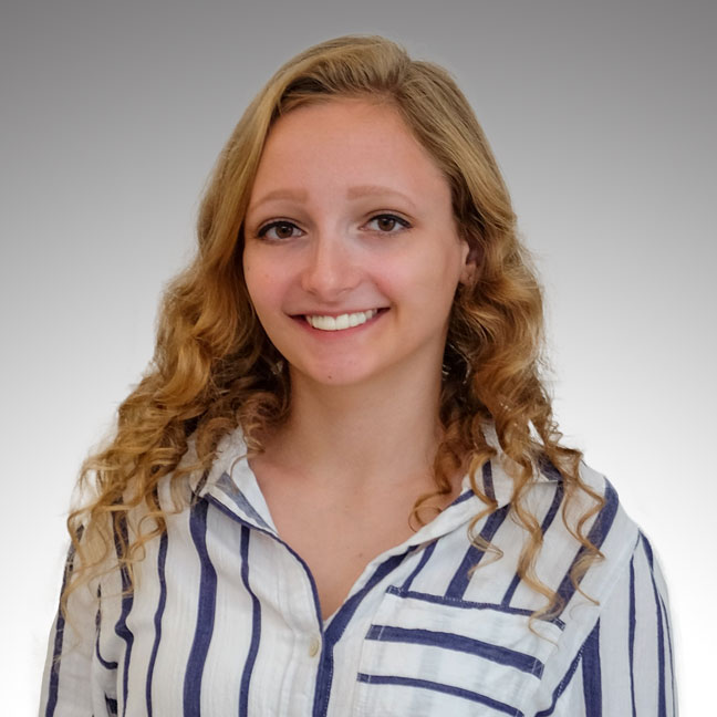 Portrait of a smiling person with curly hair, wearing a striped shirt.