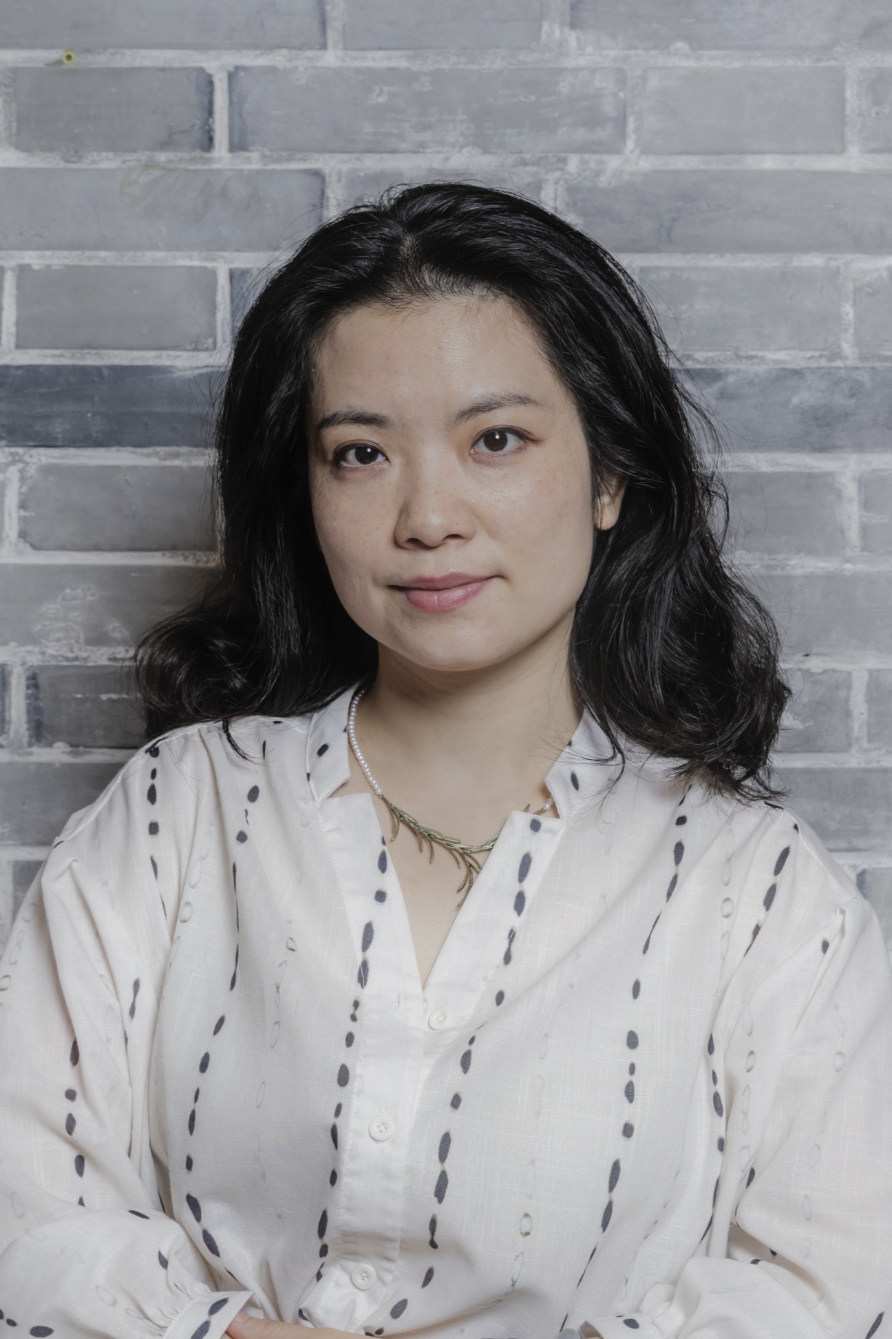 Han Qin standing in front of a white brick wall