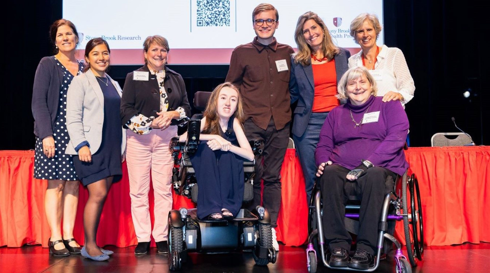 Conference attendees pose for a photo on a stage.