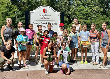 Kids show off the veggies they picked at a rooftop garden.