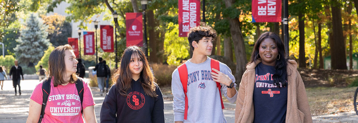 4 Students walk side by side on campus