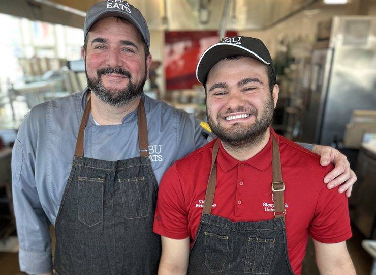 Two chefs in SBU EATS gear smiling together.