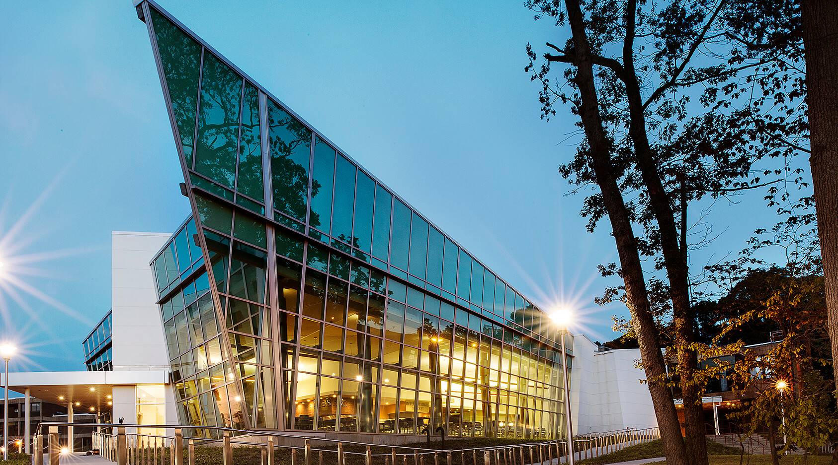 Modern glass building with angular design and trees in the foreground