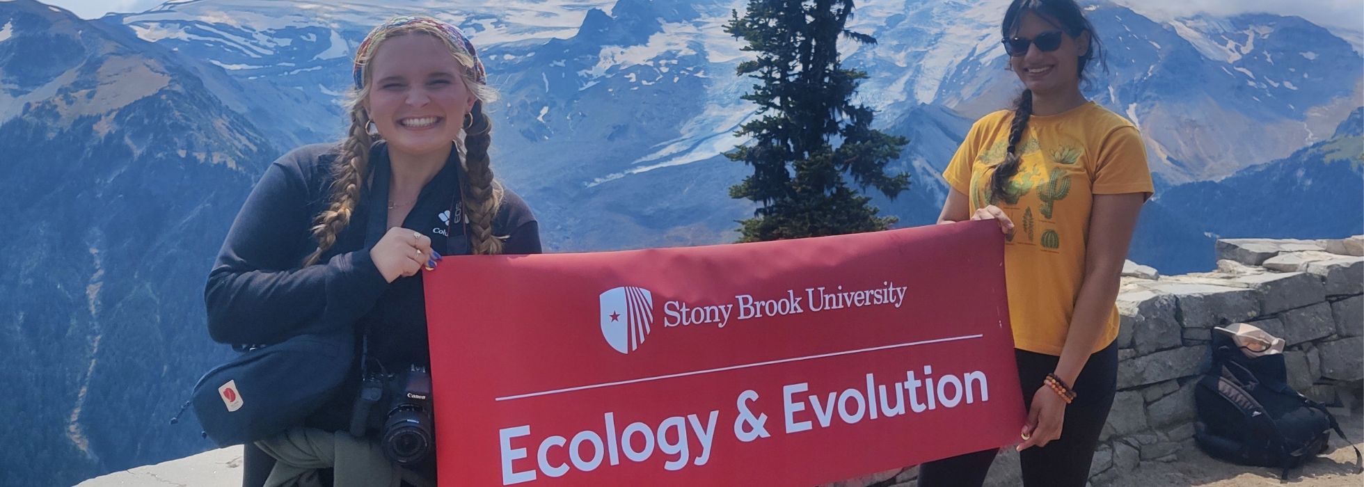 Graduate students holding an Ecology and Evolution banner in front of a high landscape.