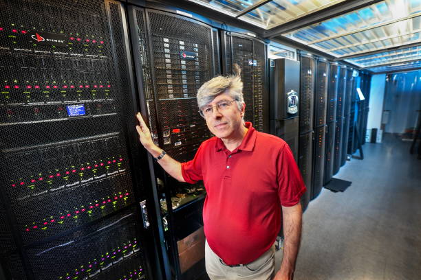 Person red shirt stands confidently in a server room, hand on a black server rack. Rows of equipment create a high-tech, professional atmosphere.