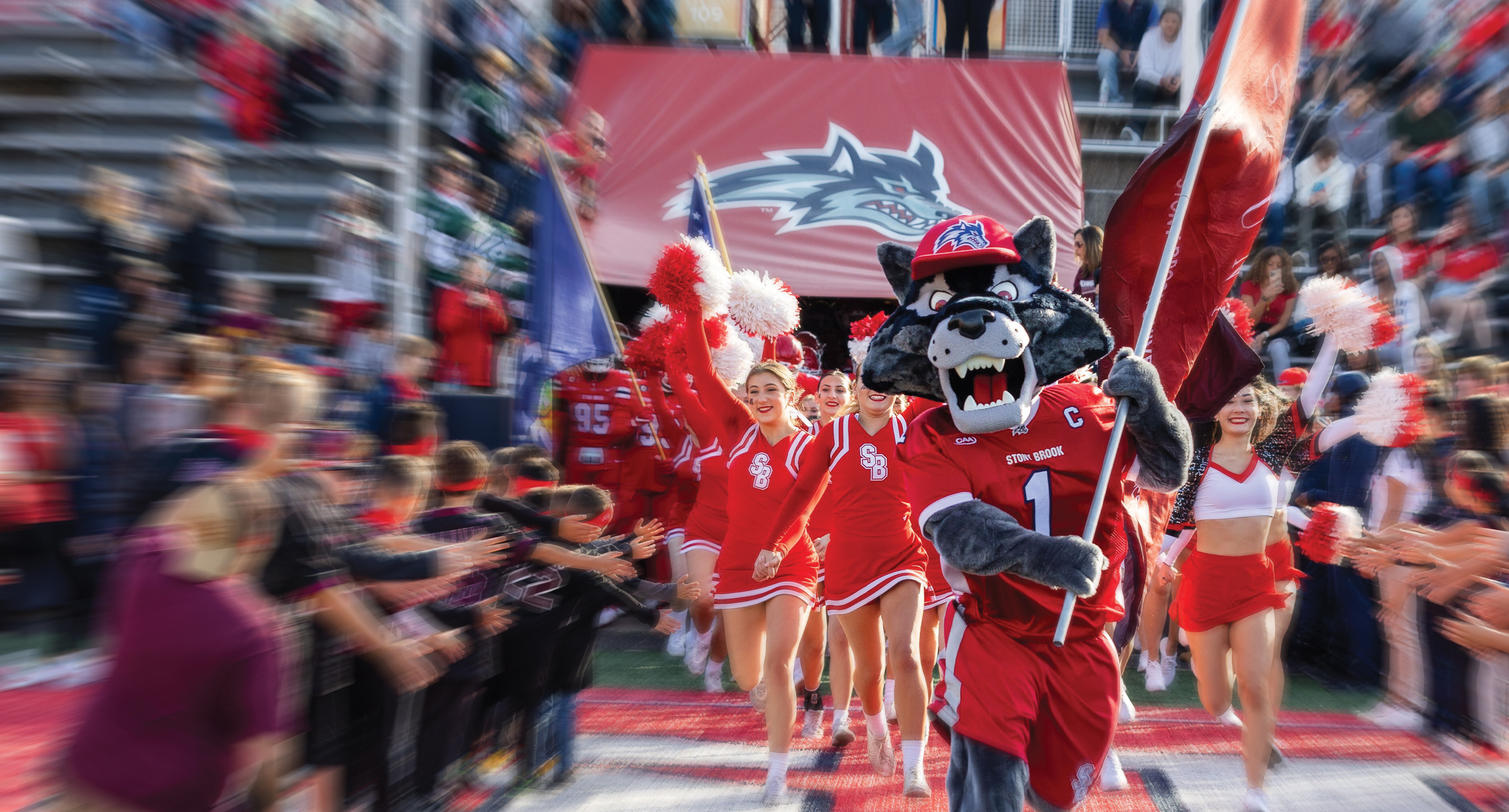 Wolfie and cheerleaders on football field with students