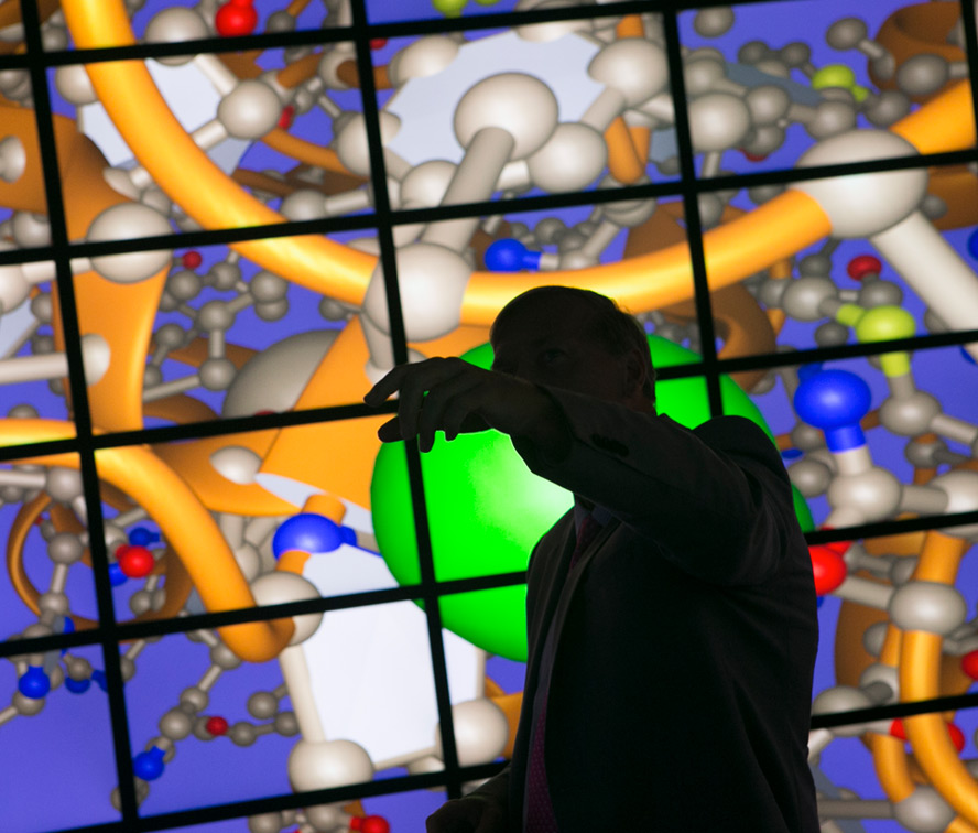 scientist looking at a large monitor with molecules on it