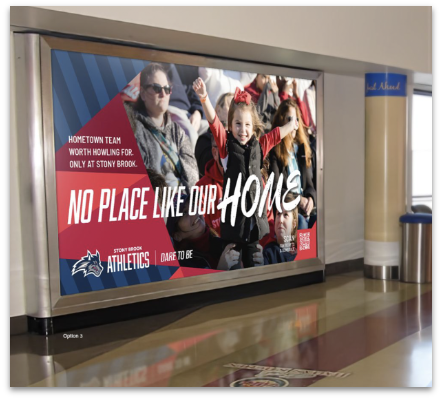 A large framed advertisement for Stony Brook Athletics is mounted on a corridor wall, featuring a crowd of fans with a young girl cheering in the center.