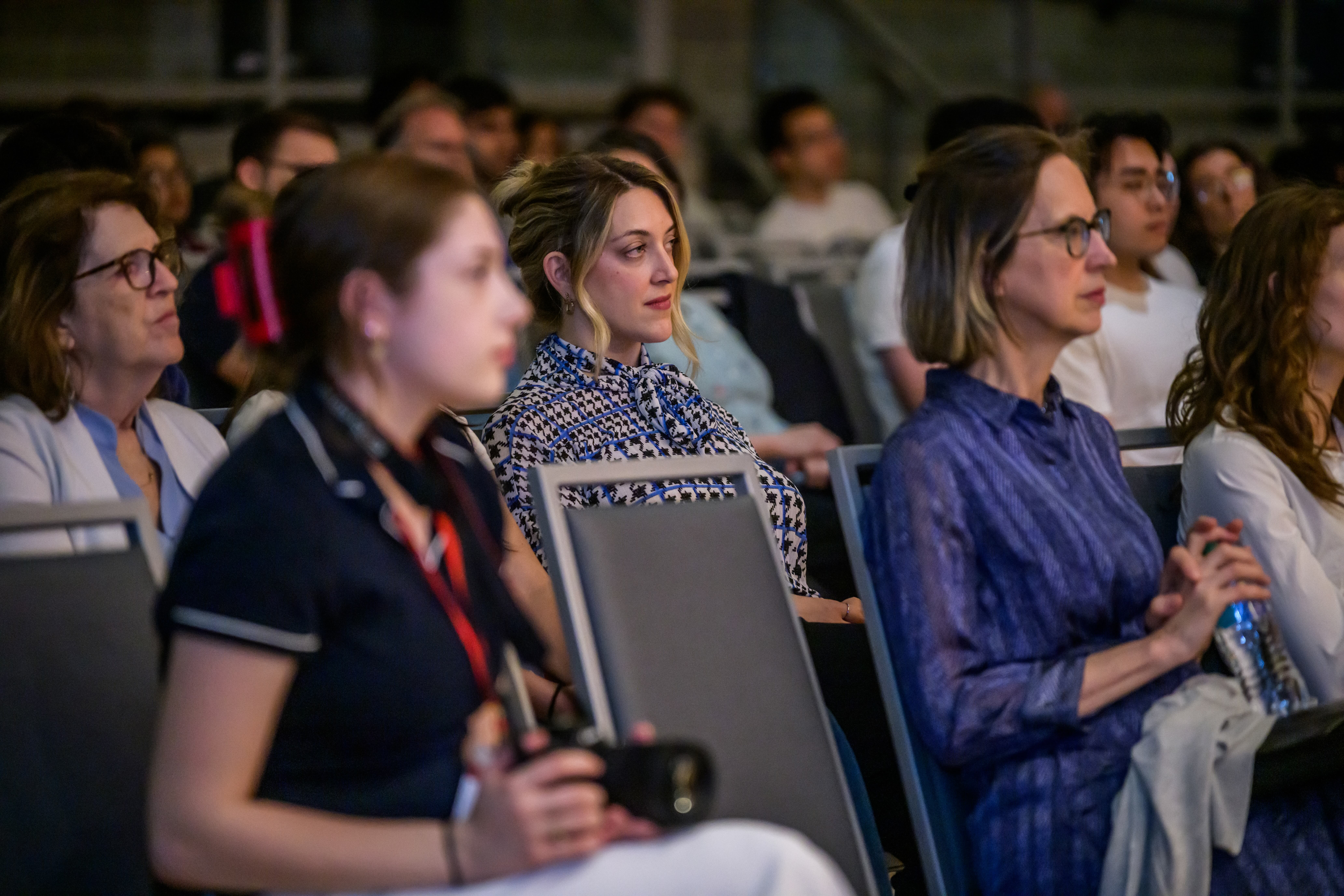 An audience sits attentively in an auditorium during an presentation or event.