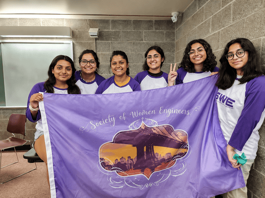CME and ESG students of the Society of Women Engineers holding a club banner during a campus event