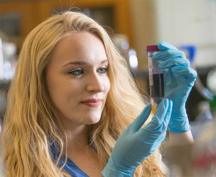 Student in lab class looking into a beaker half full of solution