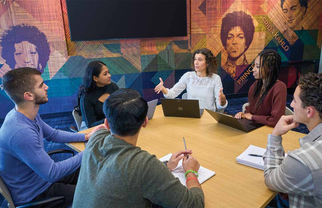 Professor speaking to a class around a conference table