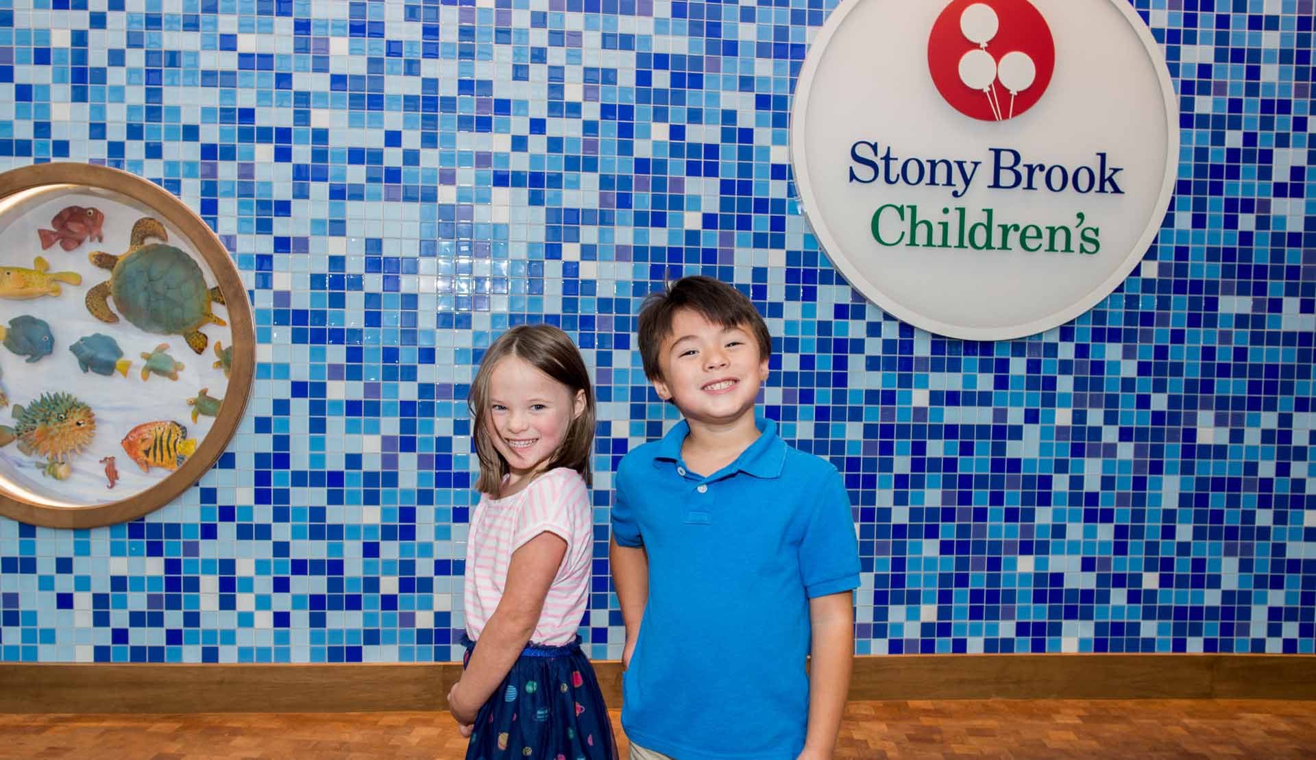 Image of two children smiling in front of the children's hospital sign