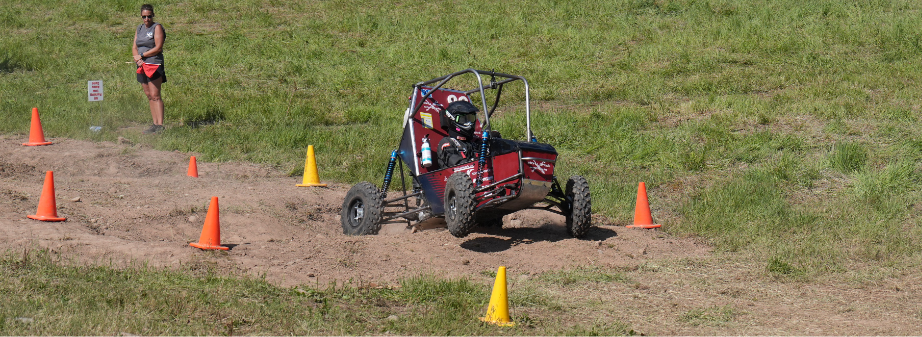 SBU's Baja car jumping over a short hill.
