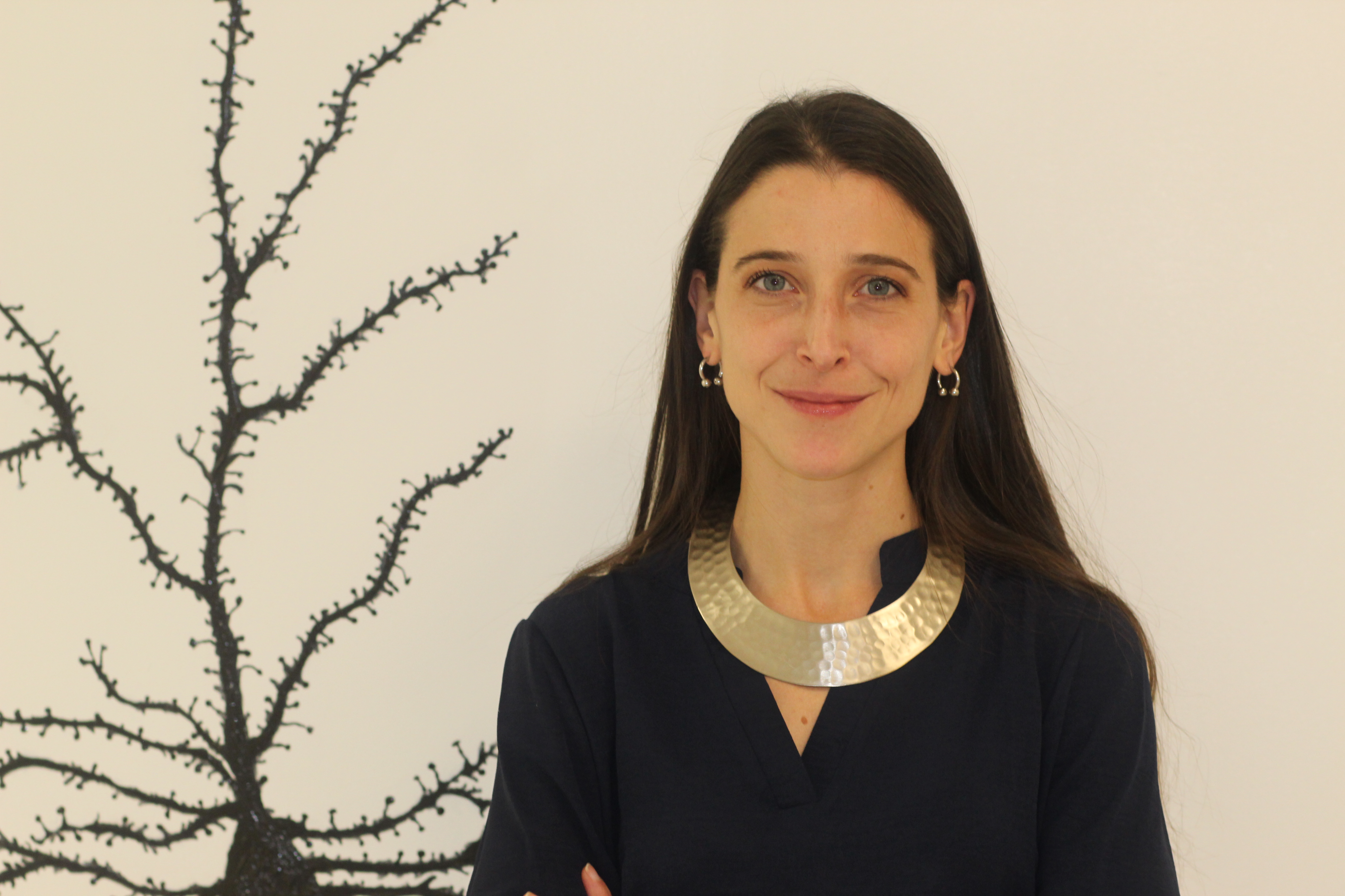Headshot of Marta Pratelli in front of neuron mural