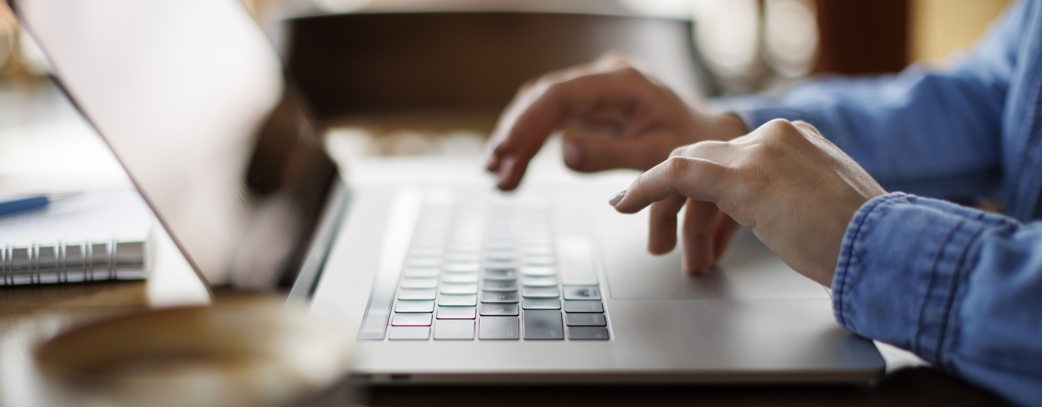 A close-up shot of a pair of hands typing on a laptop keyboard