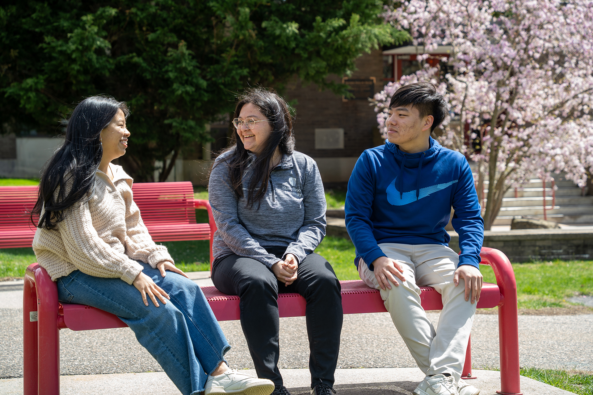 Two students speaking with a Resident Assistant on a bench