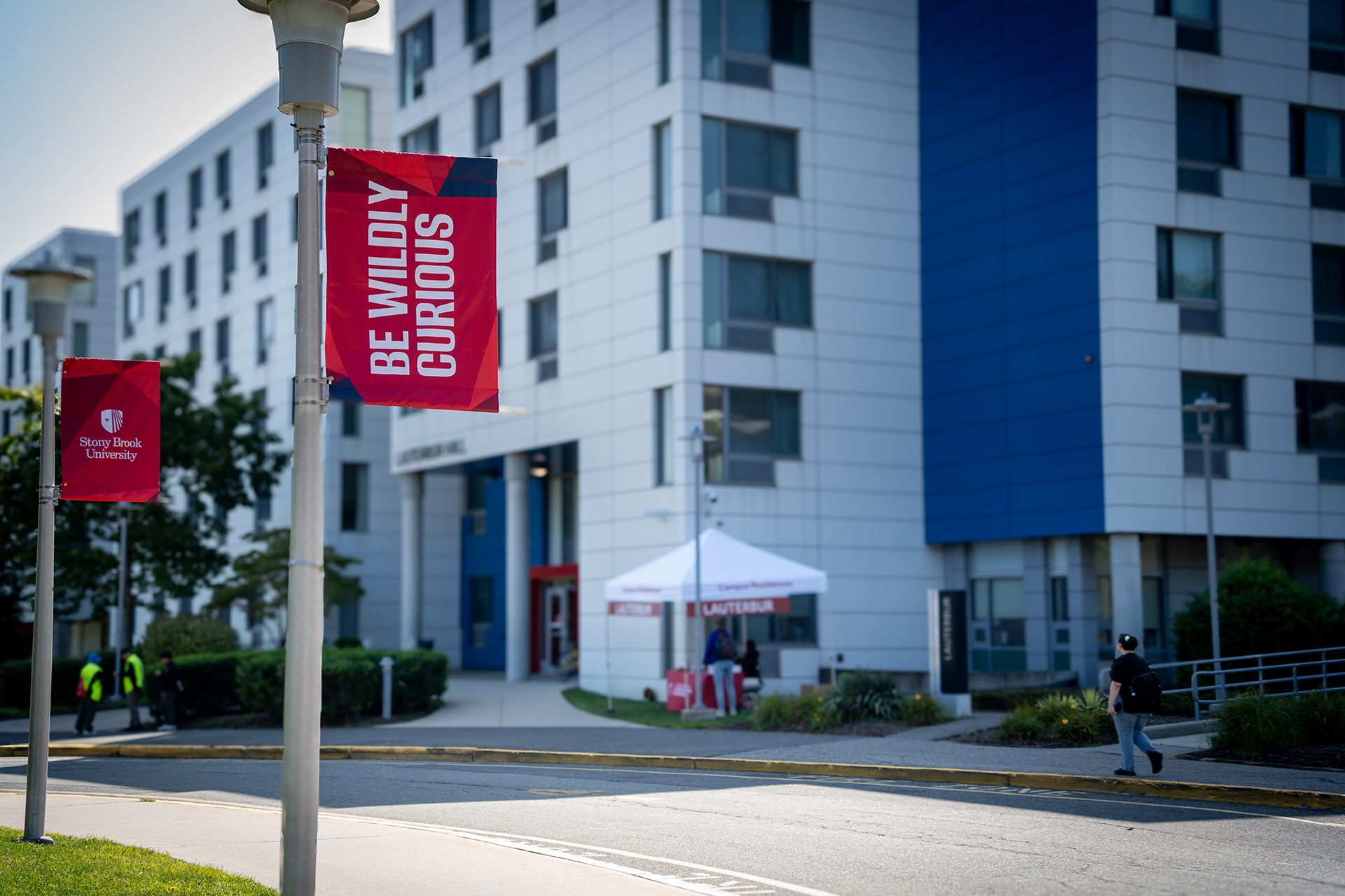 A pole flag that reads "Be Wildly Curious" outside Lauterbur residence hall