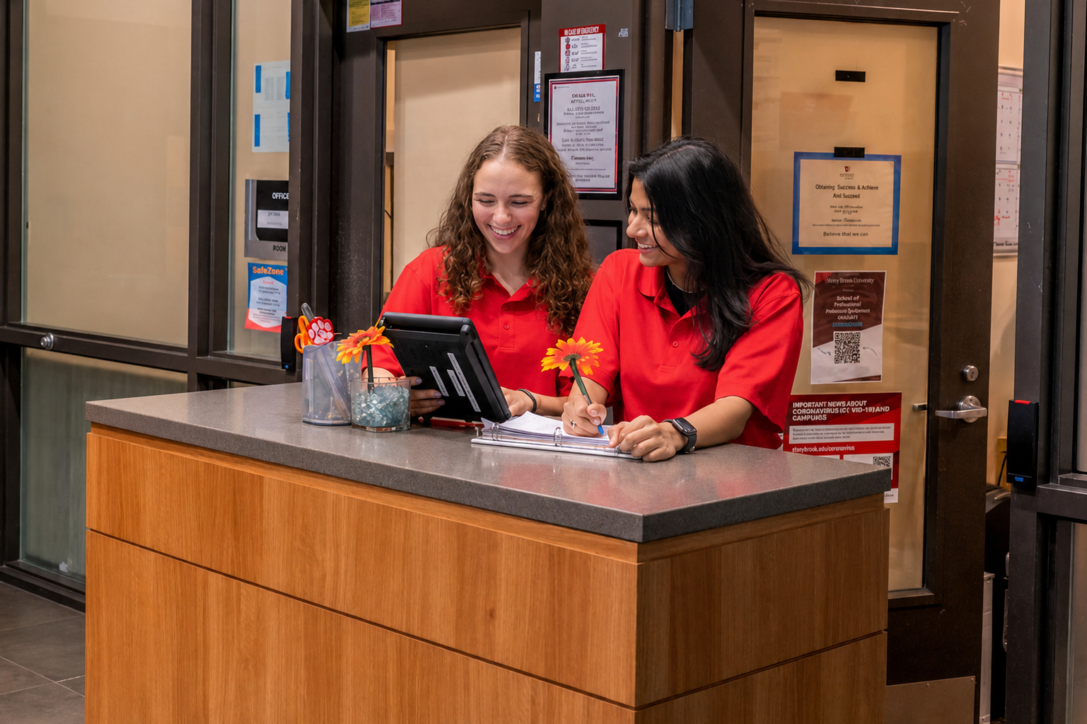 two Office Assitants work at the front desk