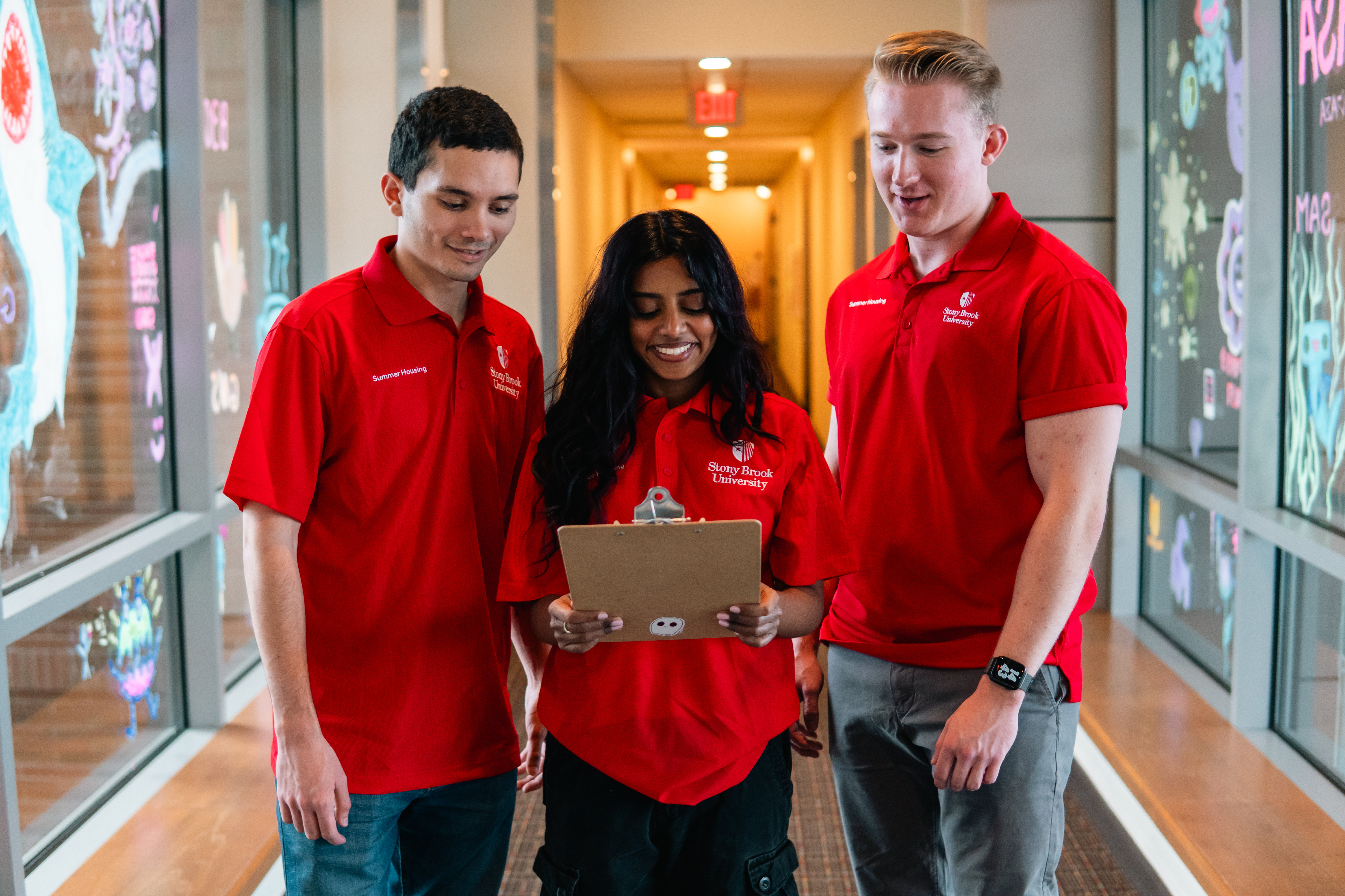 Three students walk and look at a clipboard