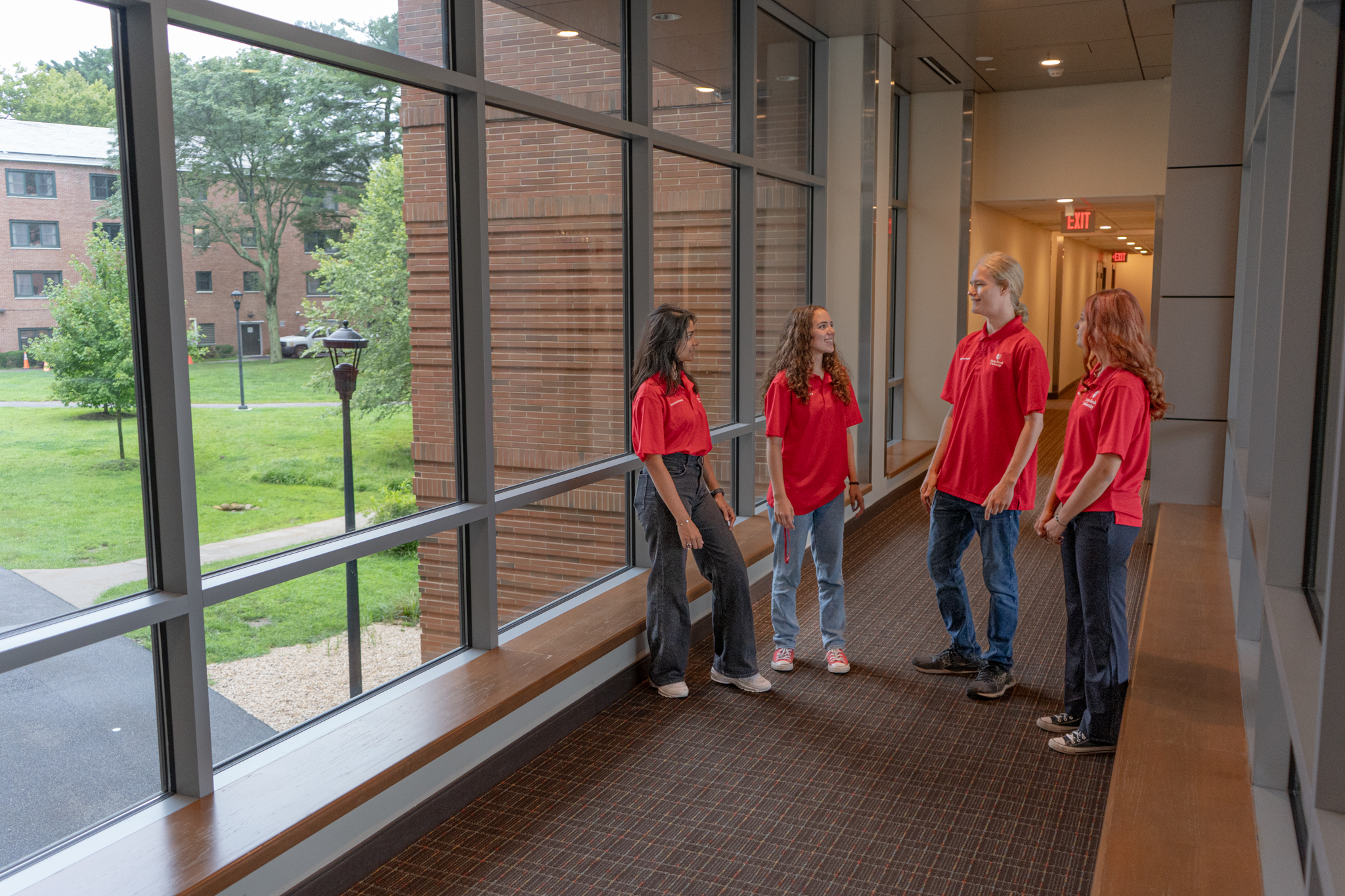 four summer housing assistants chat in a hallway