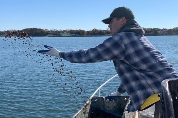Demetrios Caroussos tosses clams off the side of a research vessel