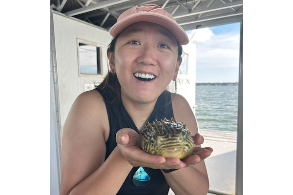 Silvia Gao holds a pufferfish onboard a research vessel
