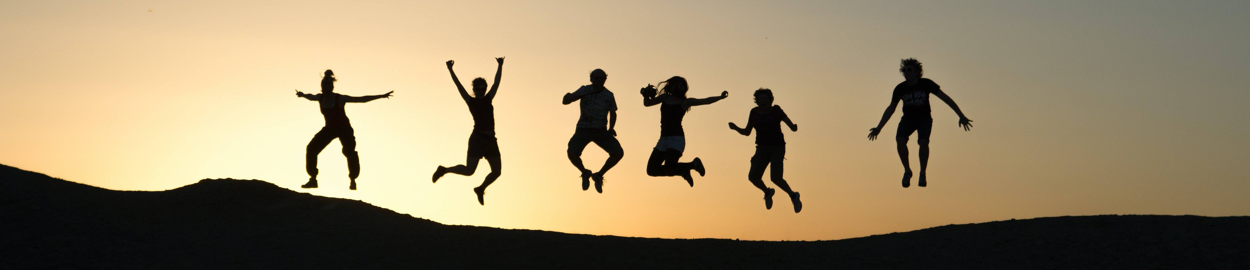 Student jumping in the air outside during sunset