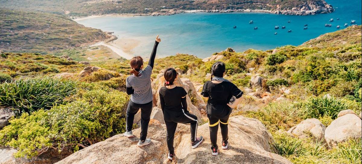 Three students hiking overlooking water